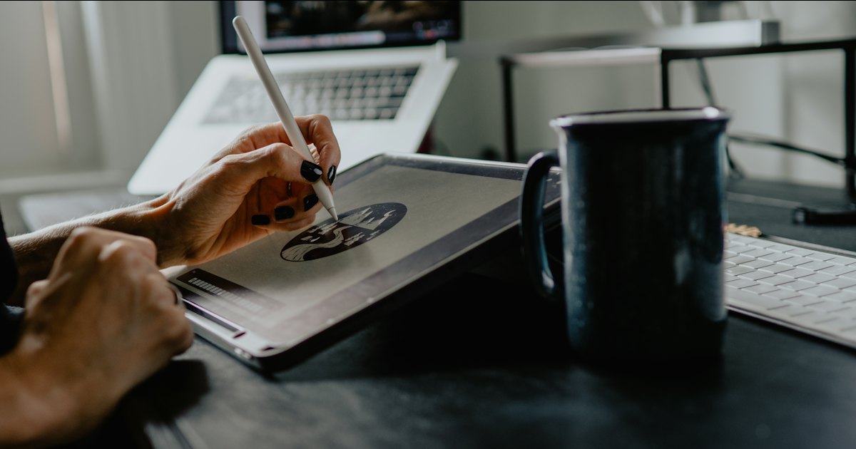 A person drawing an illustration on a tablet with a stylus at a desk