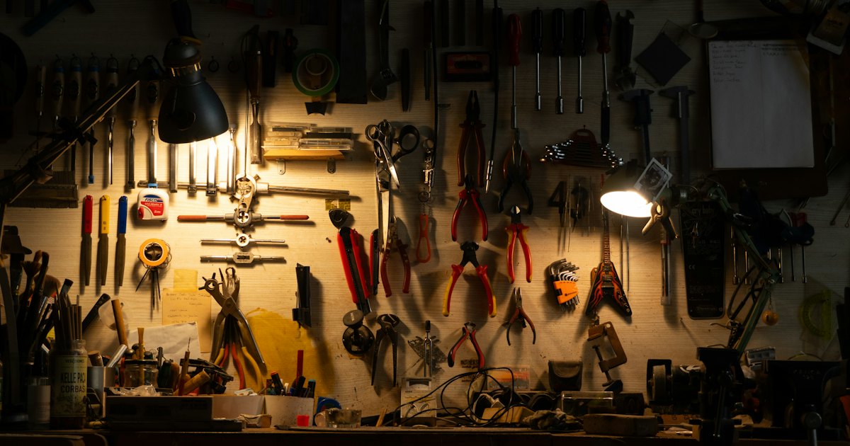 A well-lit workbench wall covered with hanging hand tools, organised by type and size