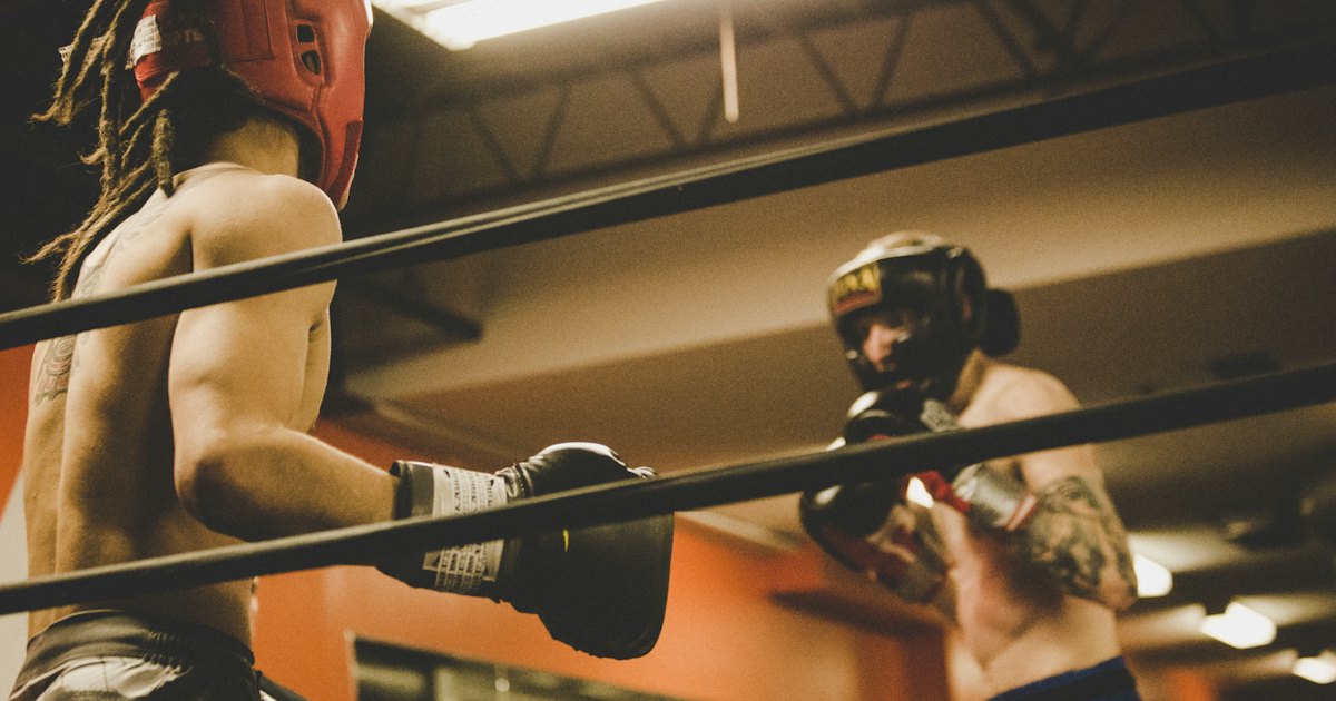 Two boxers in training gear sparring in a gym ring, gloves raised