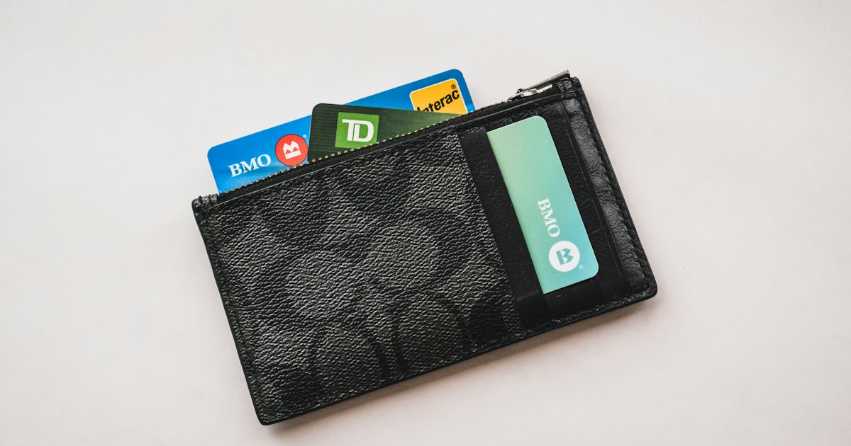 A wallet stuffed with several bank cards on a plain table