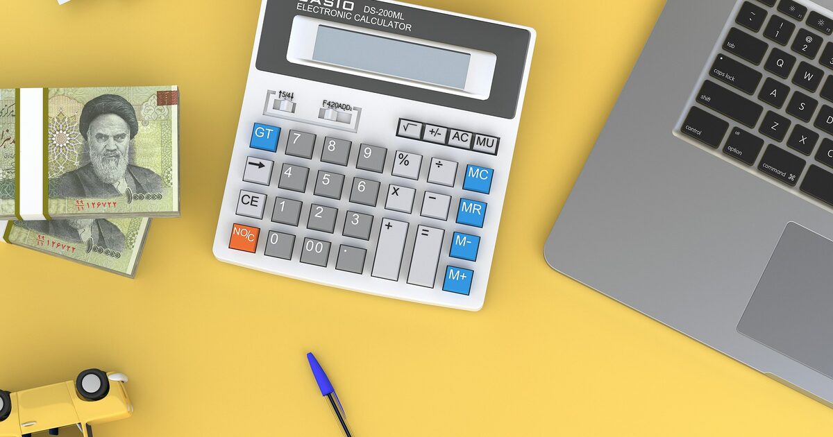 A calculator sitting on a desk next to an open laptop