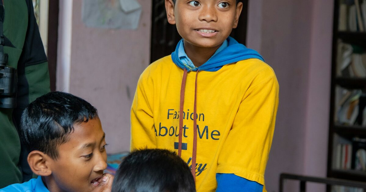 Three young Nepali schoolboys sitting together in a rural classroom