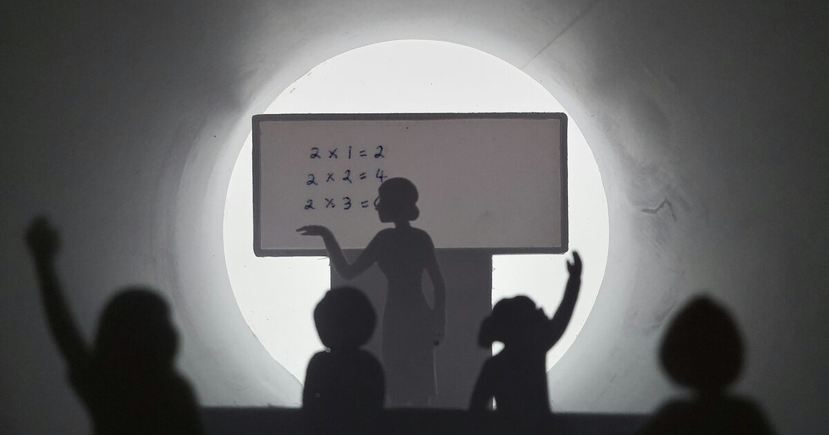 A teacher and a group of people standing in front of a whiteboard