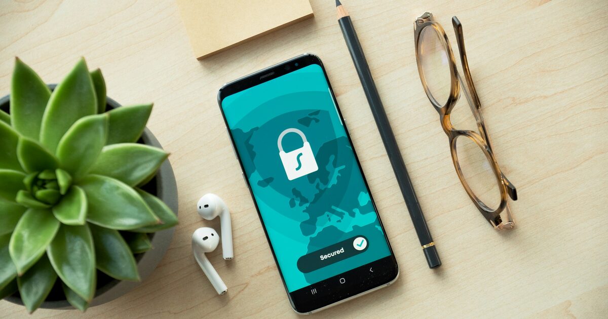 A smartphone showing a security lock icon resting on a wooden desk