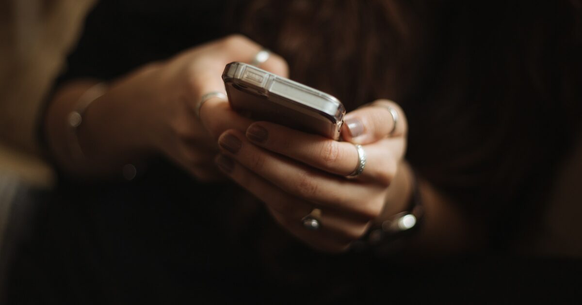 A young person casually scrolling and typing on a smartphone