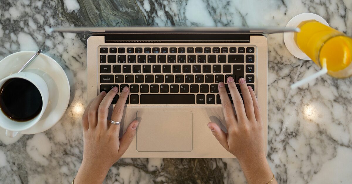 Two hands holding an open laptop computer