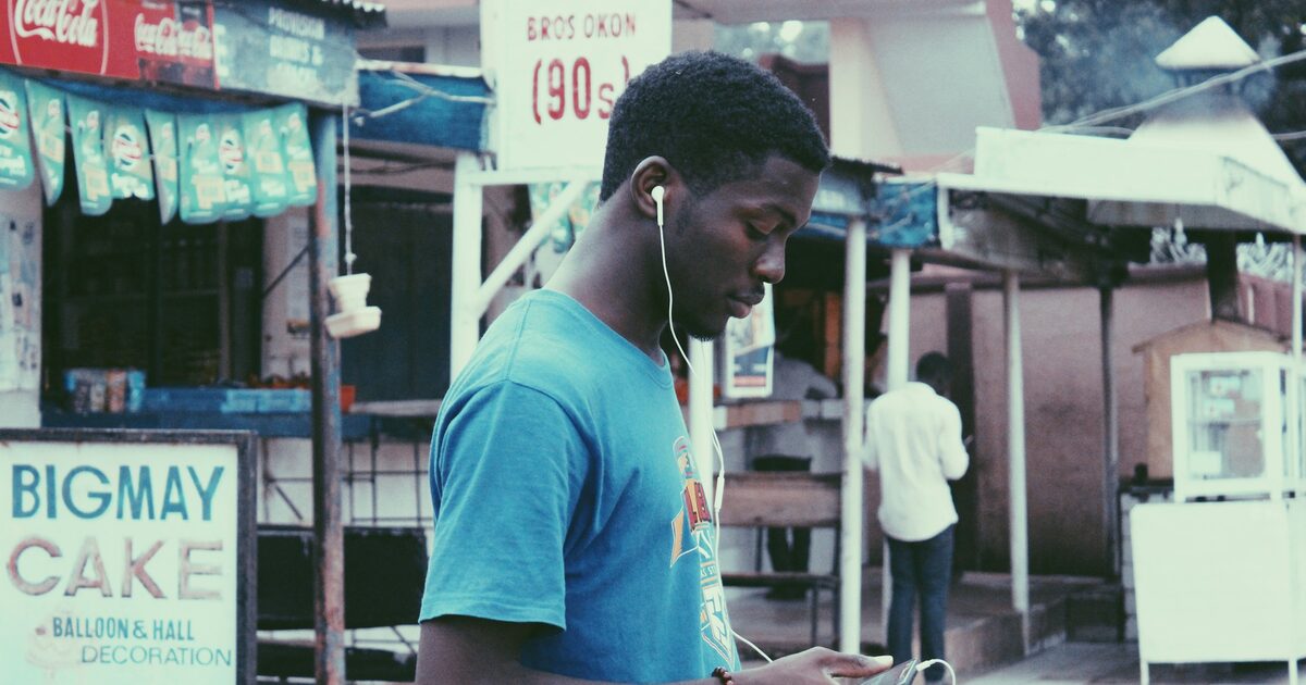 A man wearing earphones while walking near a storefront